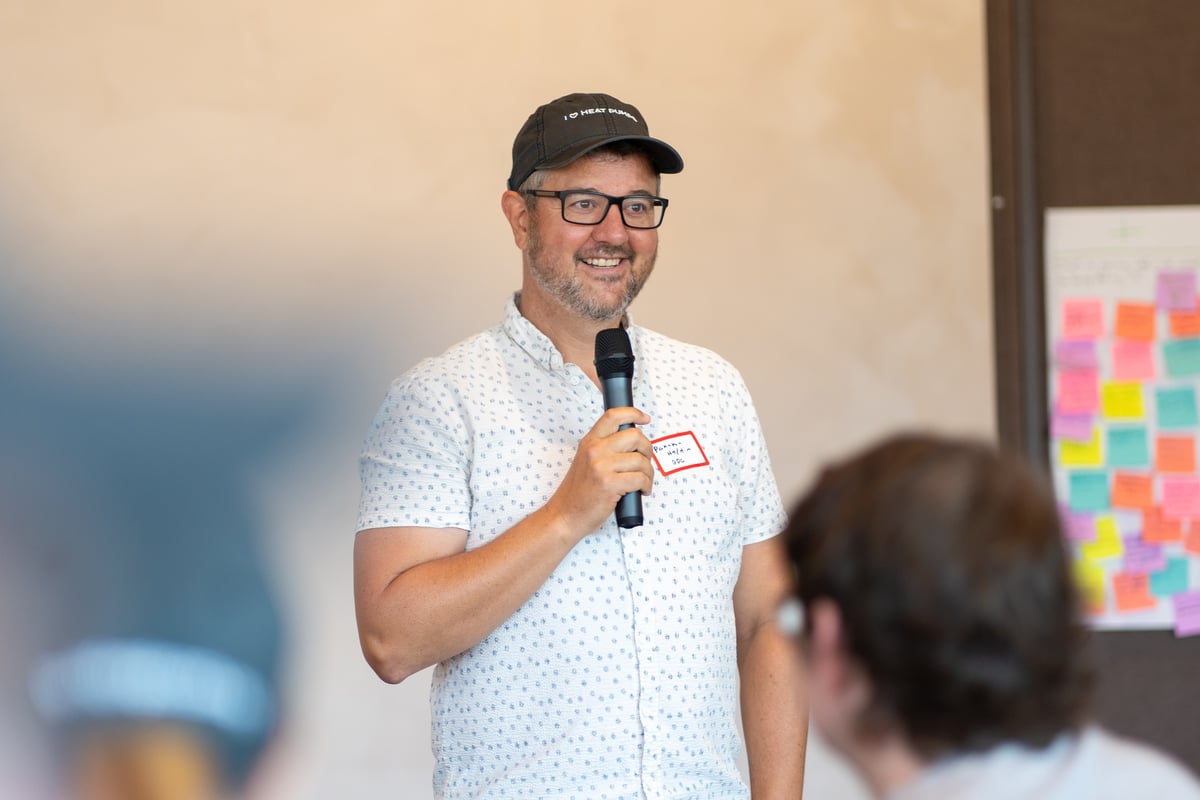 Panama Bartholomy holding a mic and smiling in front of a crowd